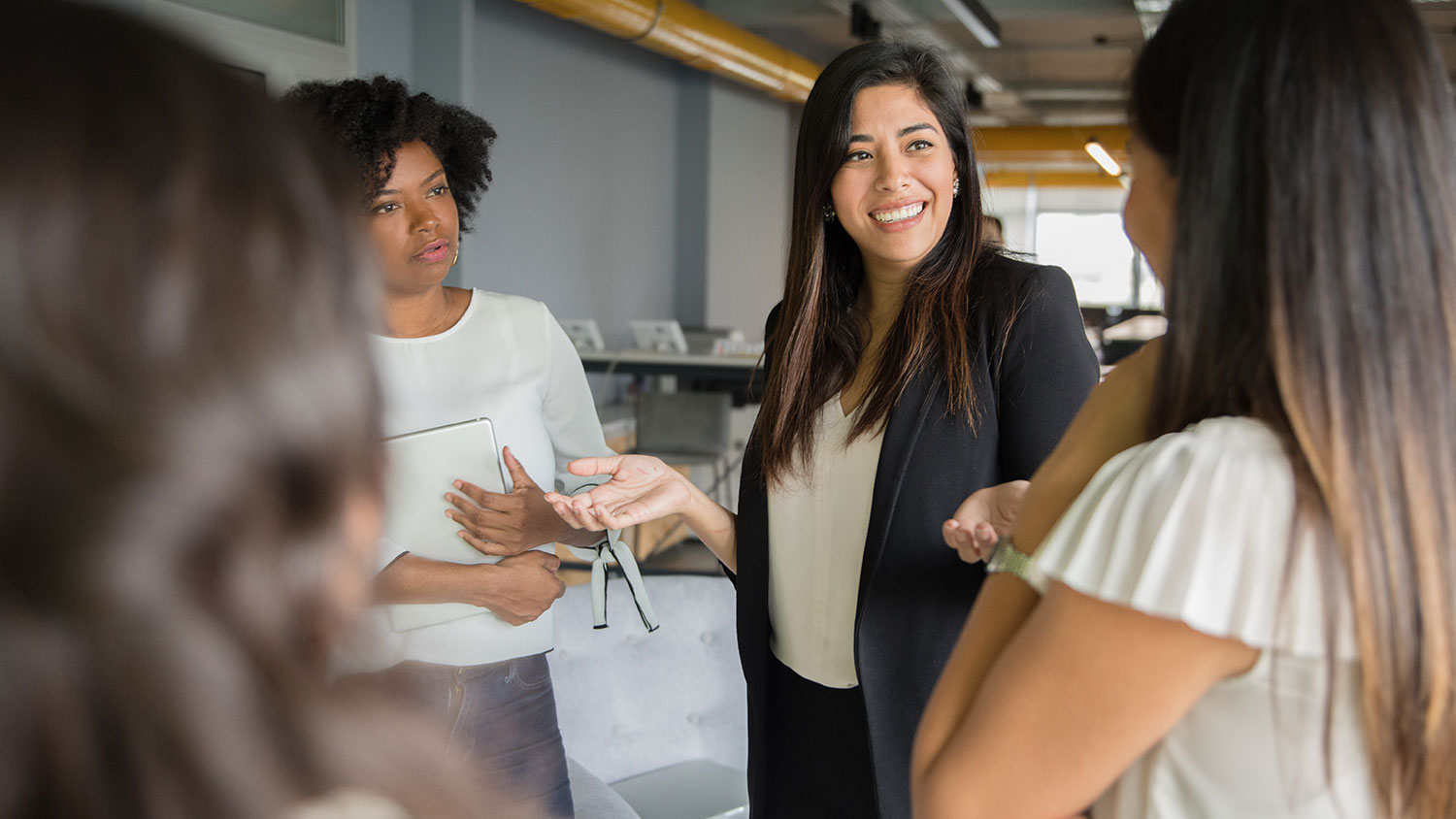 Image of a woman talking to her female colleagues